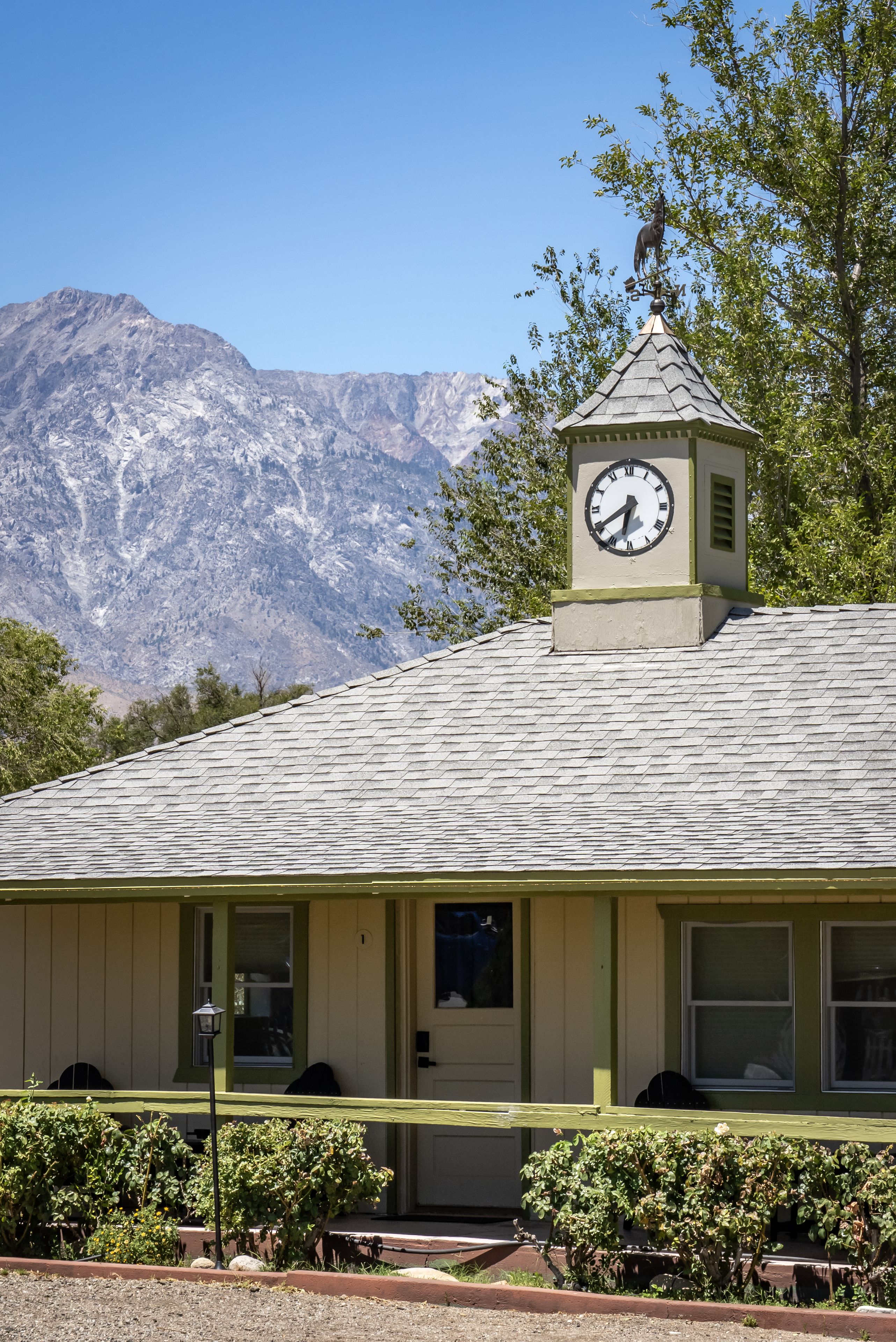A building with a clock tower, a mountain backdrop, and a clear sky.