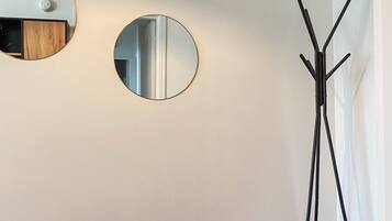 A corner room with two round mirrors on the wall, a floor lamp, and a wooden floor.