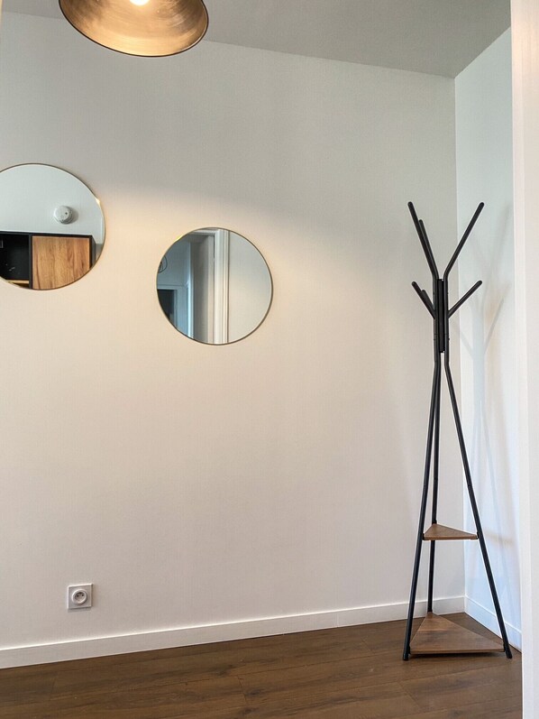 A corner room with two round mirrors on the wall, a floor lamp, and a wooden floor.