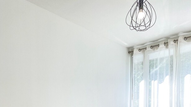 A bedroom with a bed, bedside tables, a nightstand, a lamp, and a window with curtains.