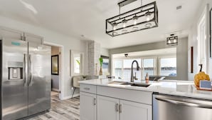 A modern kitchen with stainless steel appliances, a large island, and a view to the outside.