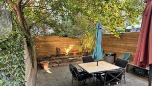 An outdoor patio with a table and chairs, a wooden fence, and a potted plant.