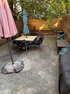 Une terrasse avec une table et des chaises, un parasol bleu et une clôture en bois.