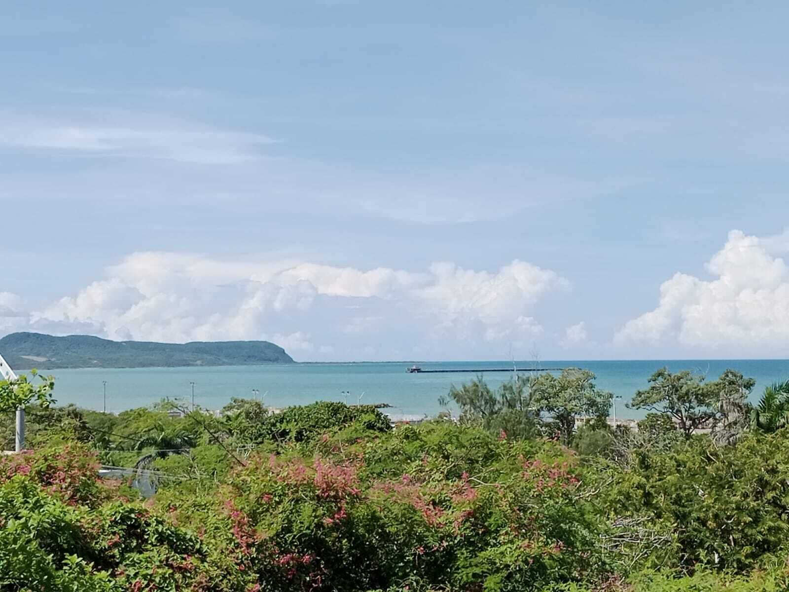 Vista costera con cielo despejado, una isla distante y una masa de agua.