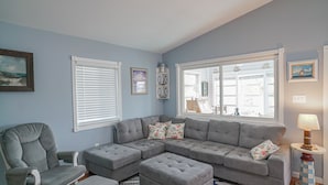 Una sala de estar con un sofá seccional gris, un sillón gris y una alfombra estampada.