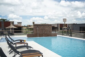 A swimming pool with lounge chairs and a brick structure with water features. - Olivos de Monte (San Miguel del Monte)