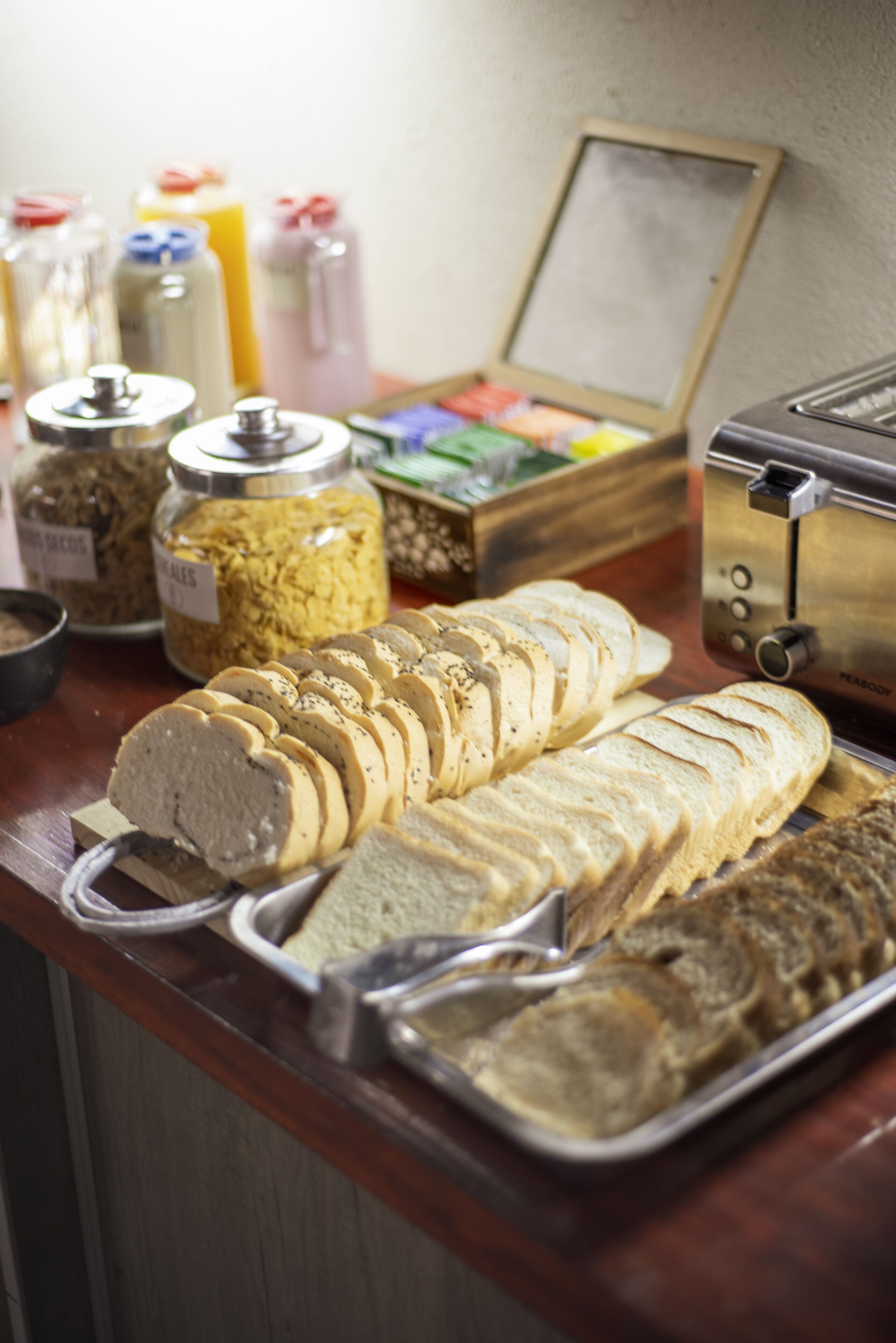 A buffet counter with sliced bread, various condiments, and a toaster.