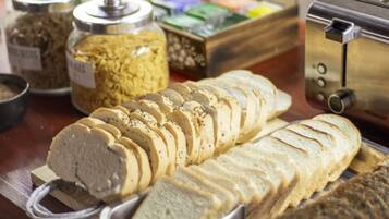 A buffet counter with sliced bread, various condiments, and a toaster.