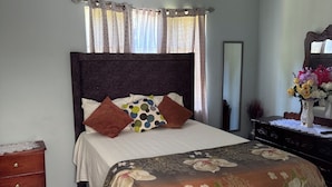 Un dormitorio con cama, cómoda, espejo y aire acondicionado.