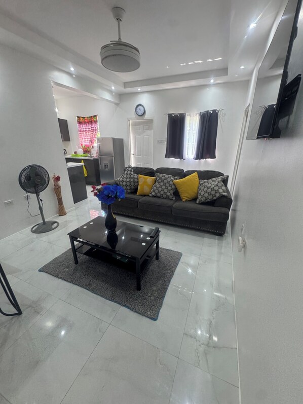 A modern living room with a sofa, coffee table, and a fan.