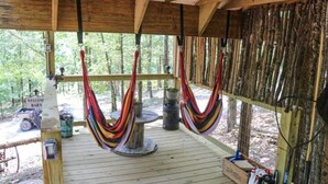 A wooden deck with a hammock, a welcome sign, and a rustic wooden wall.