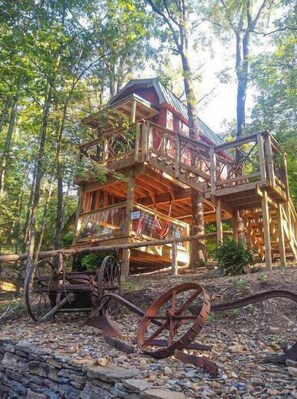 A multi-level wooden cabin with balconies, surrounded by trees. - Greers Ferry Lake Treehouses (Edgemont)