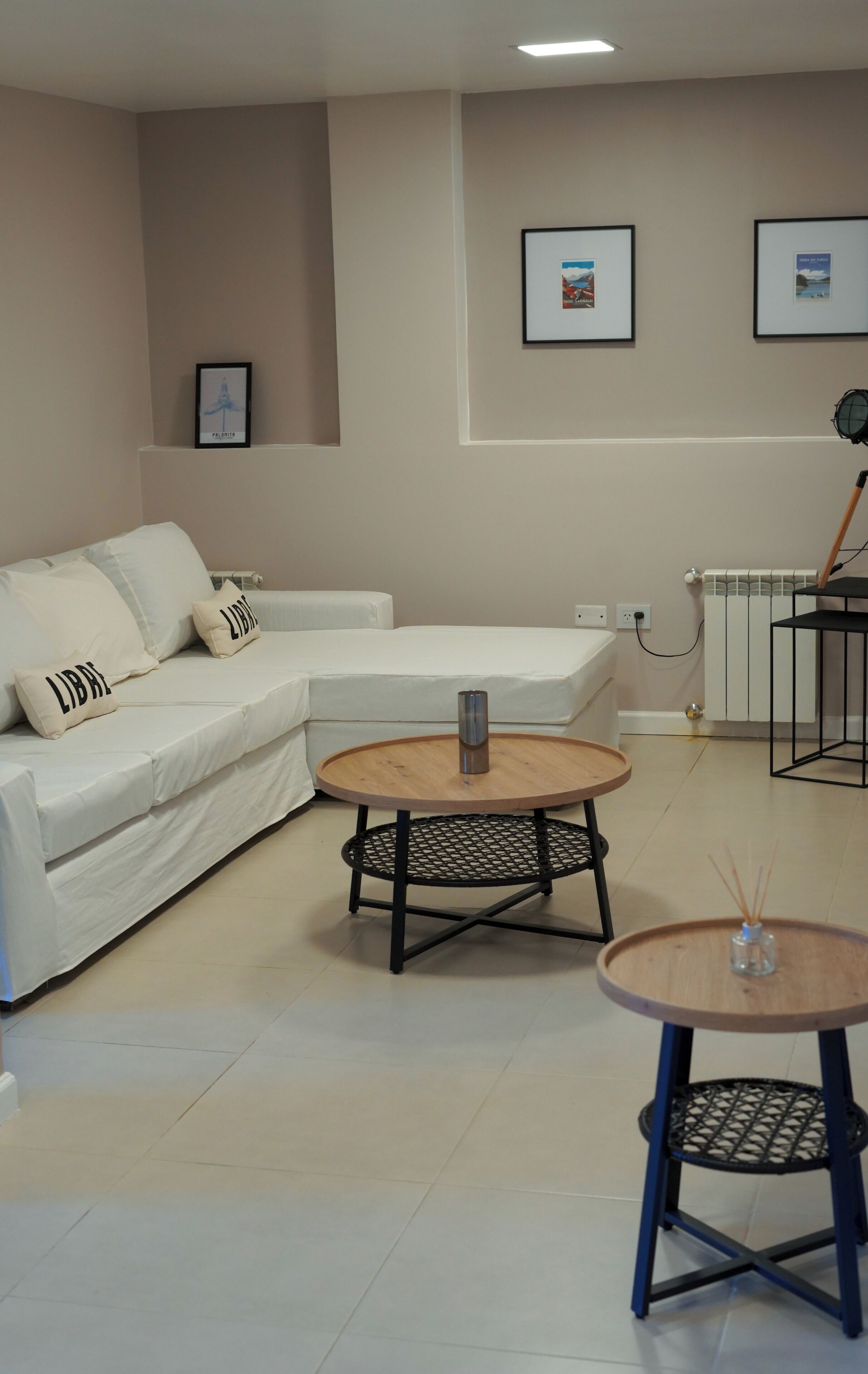 Een moderne woonkamer met een witte bank, een ronde houten salontafel en een bijzettafeltje.