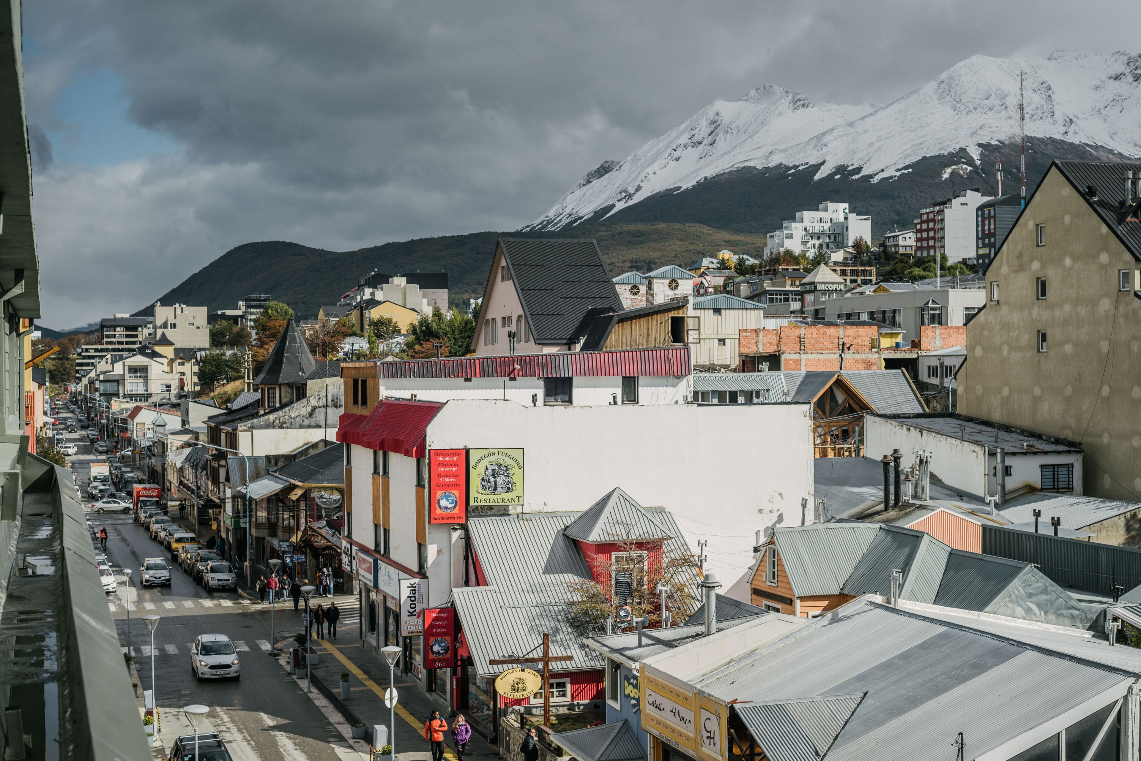 Une vue de rue avec des bâtiments, une enseigne de restaurant et une montagne en arrière-plan.