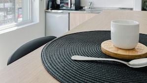 A modern kitchen with a wooden table, a black placemat, a white mug, and a spoon. - Gente del Sur - Yehuin (Ushuaia)