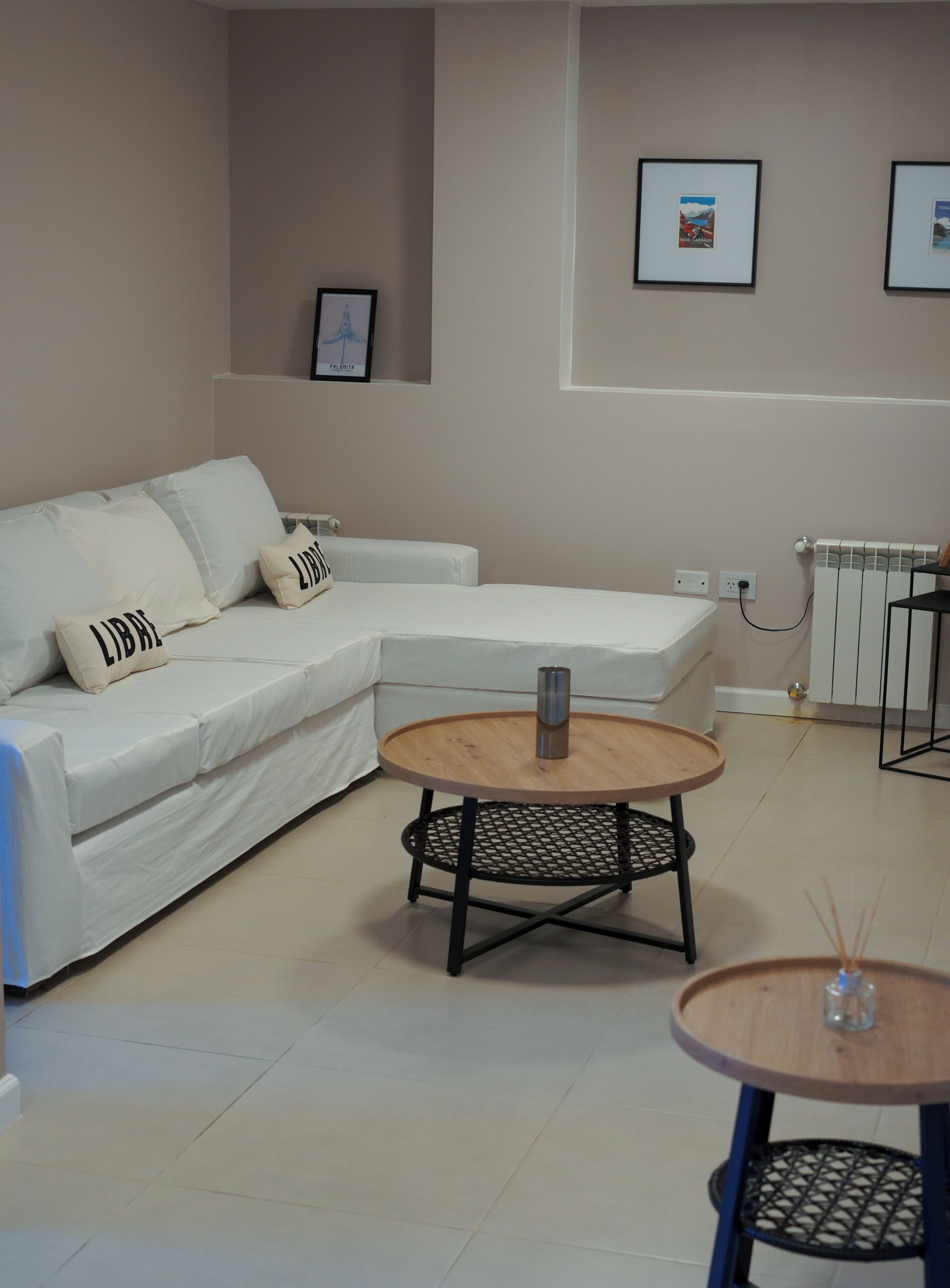 Un salon moderne avec un canapé d’angle blanc, une table basse ronde en bois et une petite table d’appoint.
