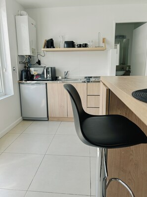 Une cuisine moderne au design épuré, comprenant un réfrigérateur, un four à micro-ondes et un évier.