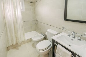 Une salle de bain moderne équipée d’une baignoire, d’un bidet, de toilettes et d’un grand lavabo.