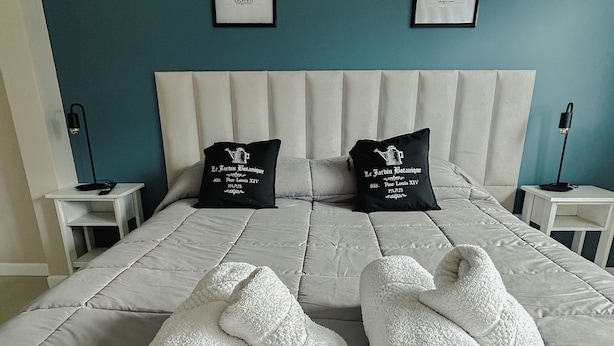 A neatly made bed with two pillows, a headboard, and two framed botanical prints on the wall. - Gente del Sur - Yehuin (Ushuaia)