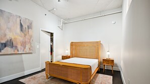 Una habitación con una cama grande, mesitas de noche, un armario y un cuadro en la pared.