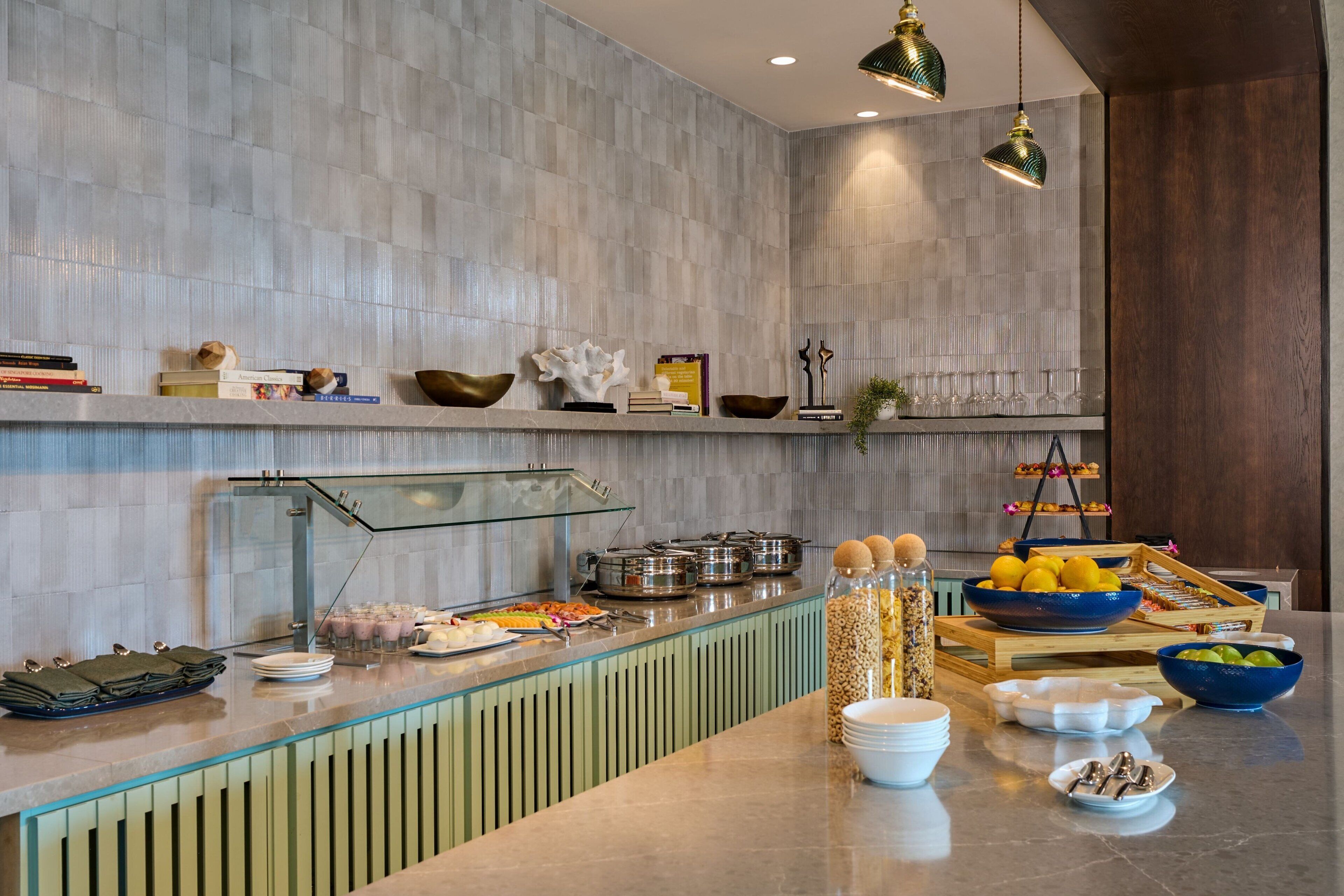 Zona de buffet con diversos alimentos, una vitrina de vidrio y una barra de madera.