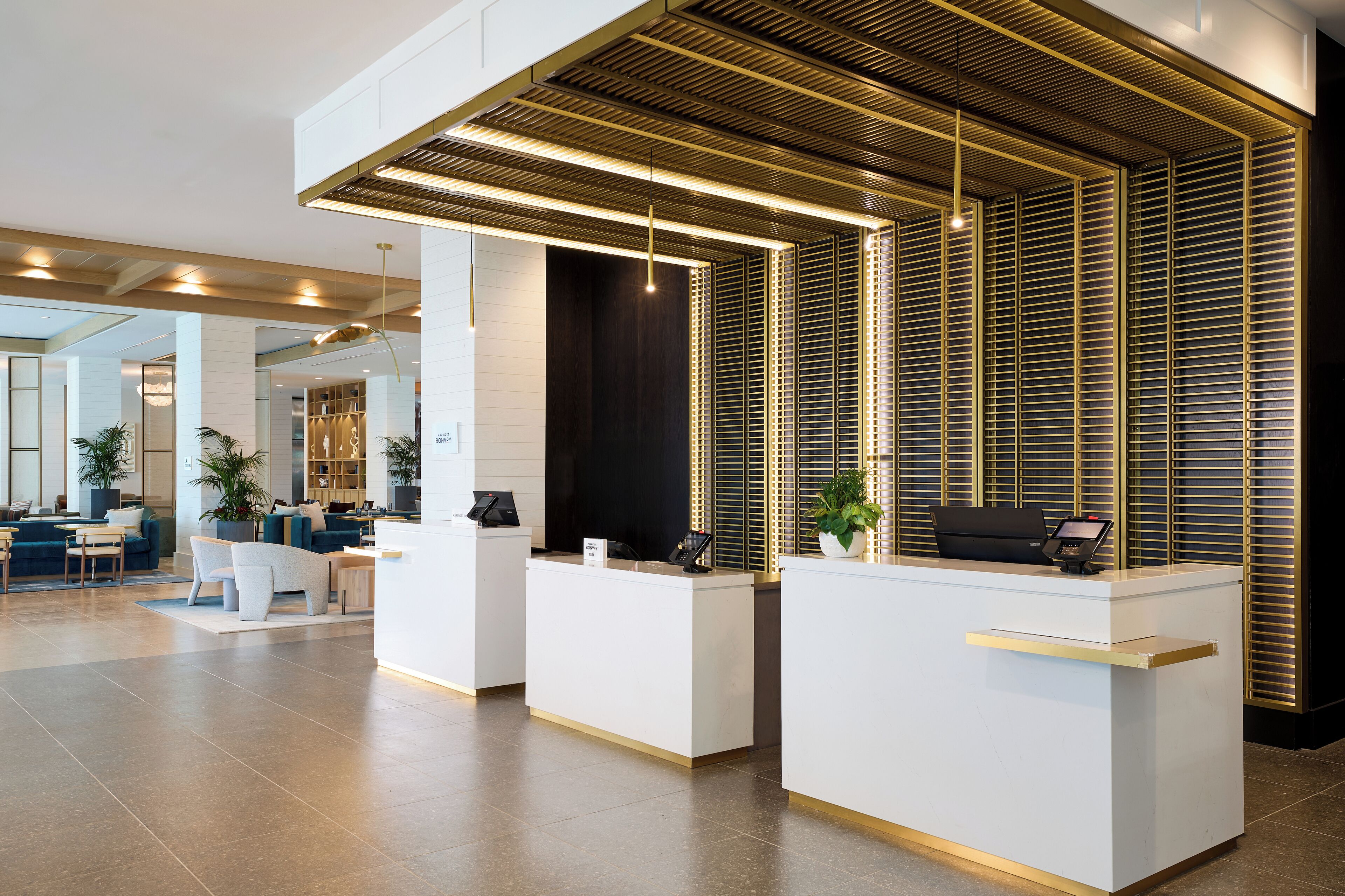 A modern reception area with a clean, minimalist design, featuring a reception desk, seating area, and a decorative wooden ceiling.
