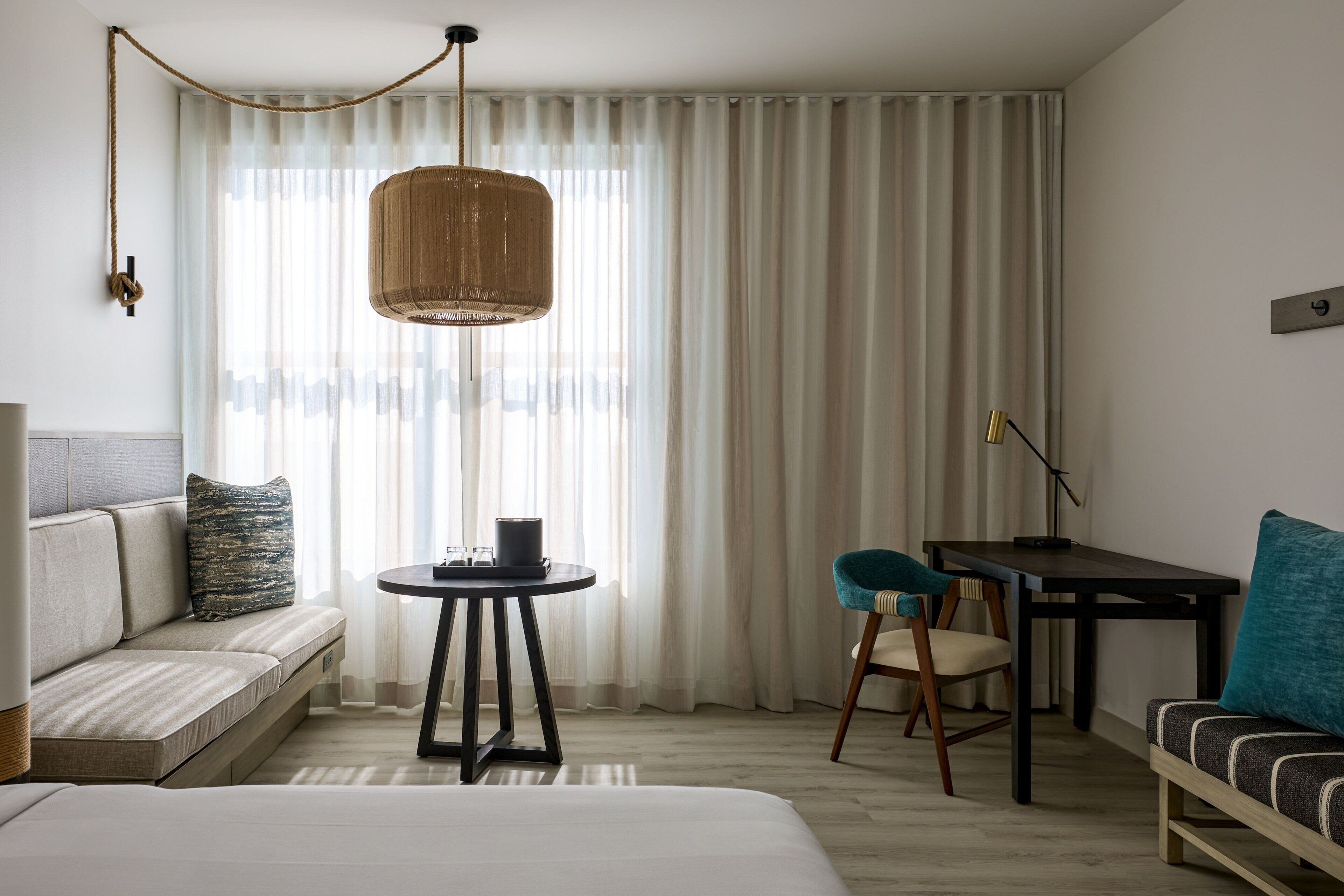 Una habitación de hotel con una cama, un sofá, una mesita, una silla y un escritorio.