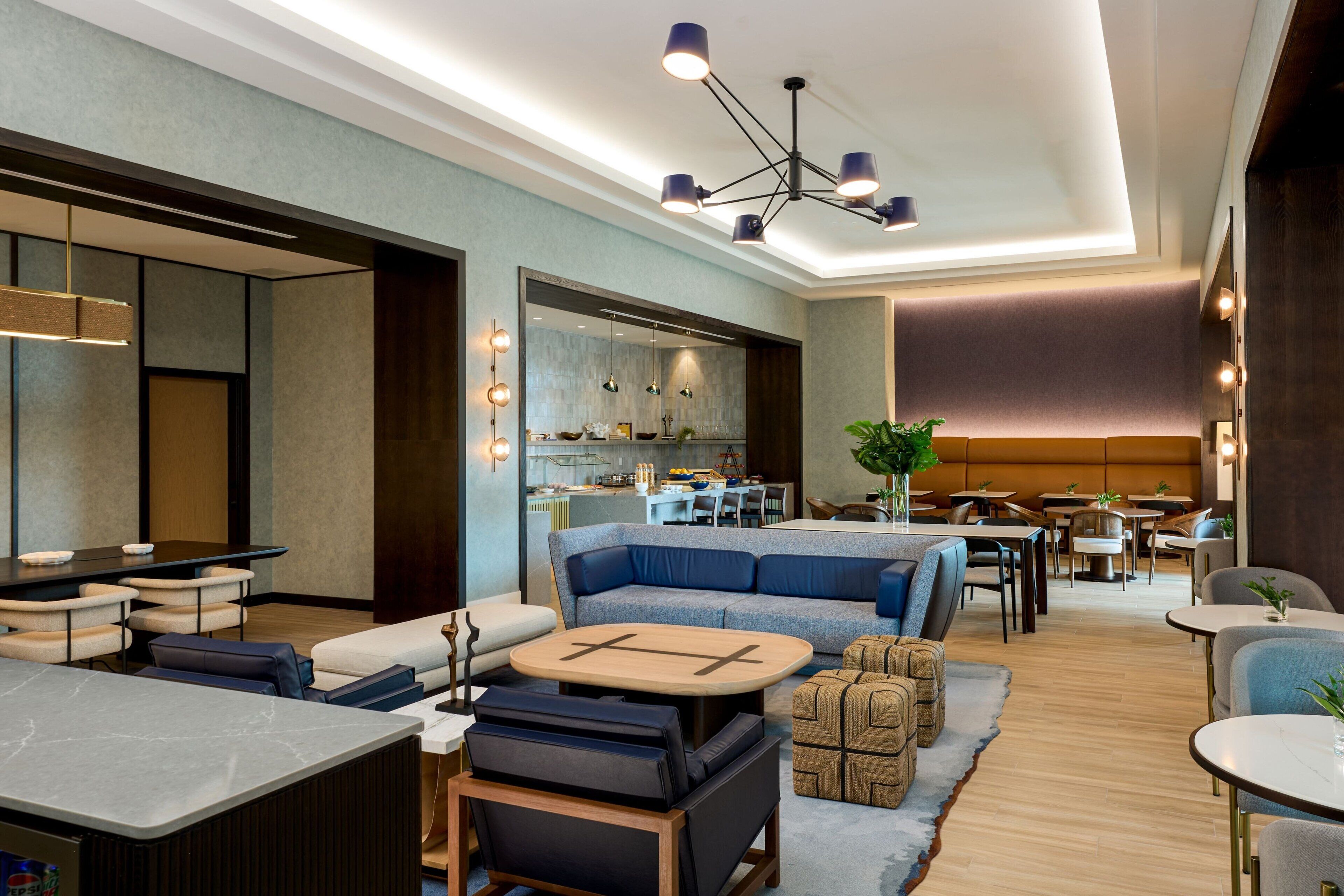 Eine moderne Hotelhalle mit Sitzgelegenheiten, einer Bar und einer Küche im Hintergrund.