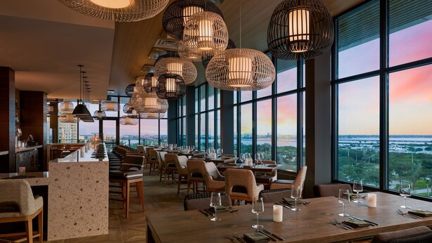 A restaurant with a long counter, multiple tables, and hanging spherical light fixtures. - Palmetto Marriott Resort & Spa (Palmetto)