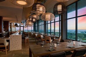 A restaurant with a long counter, multiple tables, and hanging spherical light fixtures. - Palmetto Marriott Resort & Spa (Palmetto)