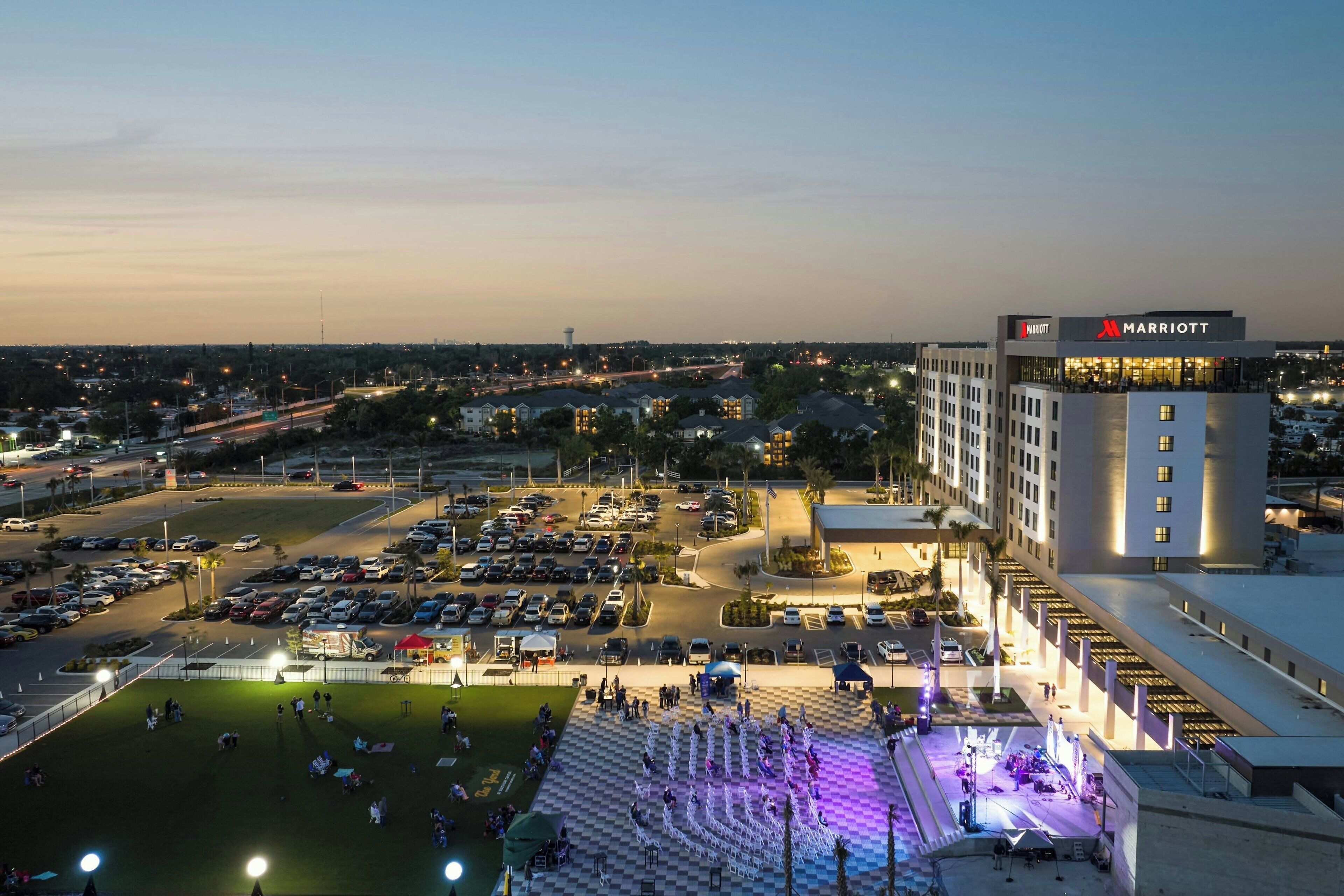 A Marriott hotel with a parking lot, a stage with performers, and a view of the surrounding cityscape.