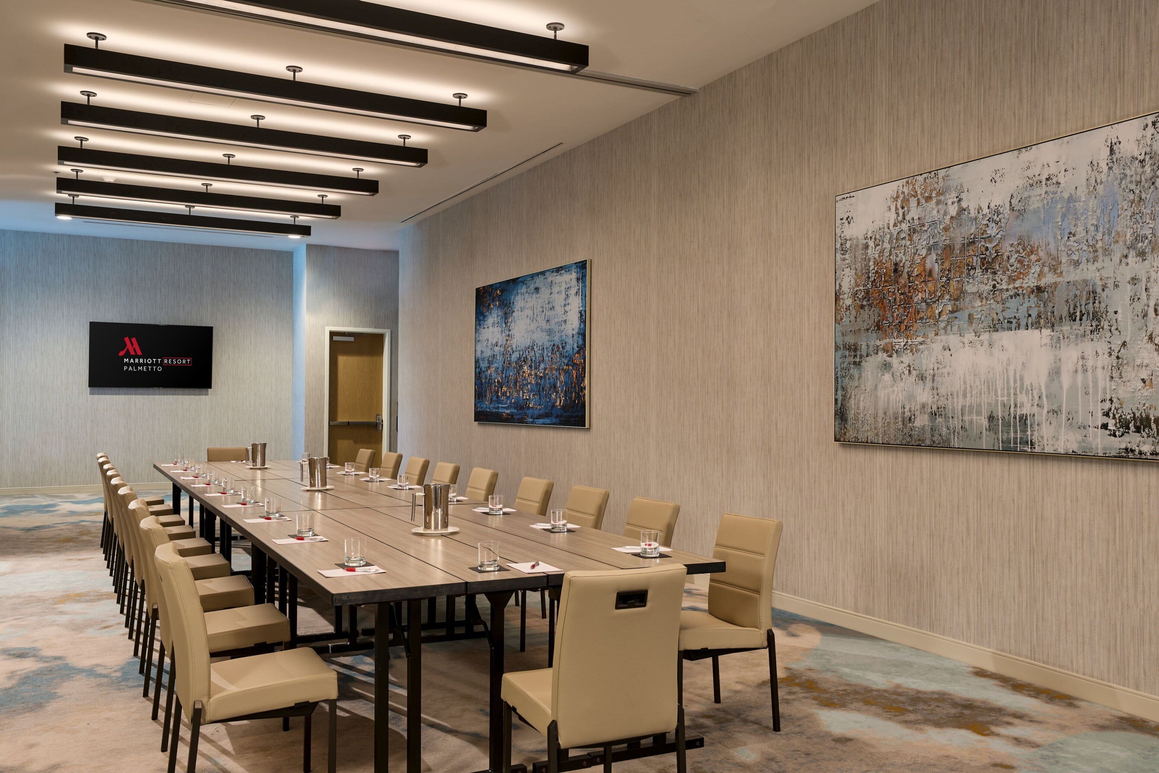 A conference room with a long table, chairs, and a large abstract painting on the wall.