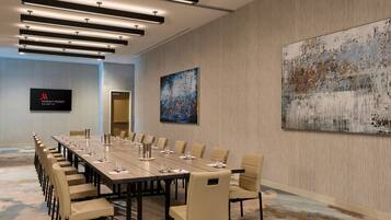 A conference room with a long table, chairs, and a large abstract painting on the wall.