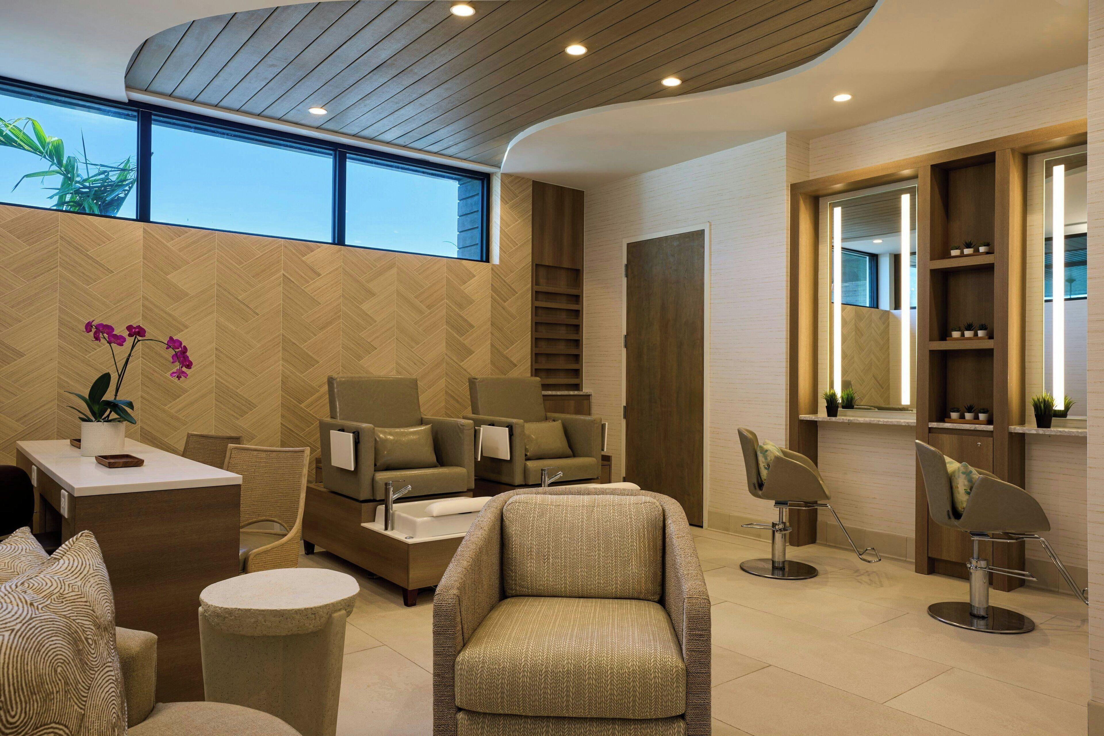 A modern interior with a herringbone-patterned wall, a seating area with sofas and chairs, a reception desk, and a staircase.