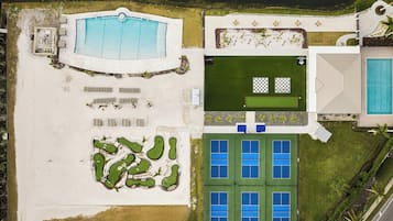 Eine Vogelperspektive zeigt einen luxuriösen Urlaubsort mit Schwimmbad, Golfplatz und Tennisplätzen.