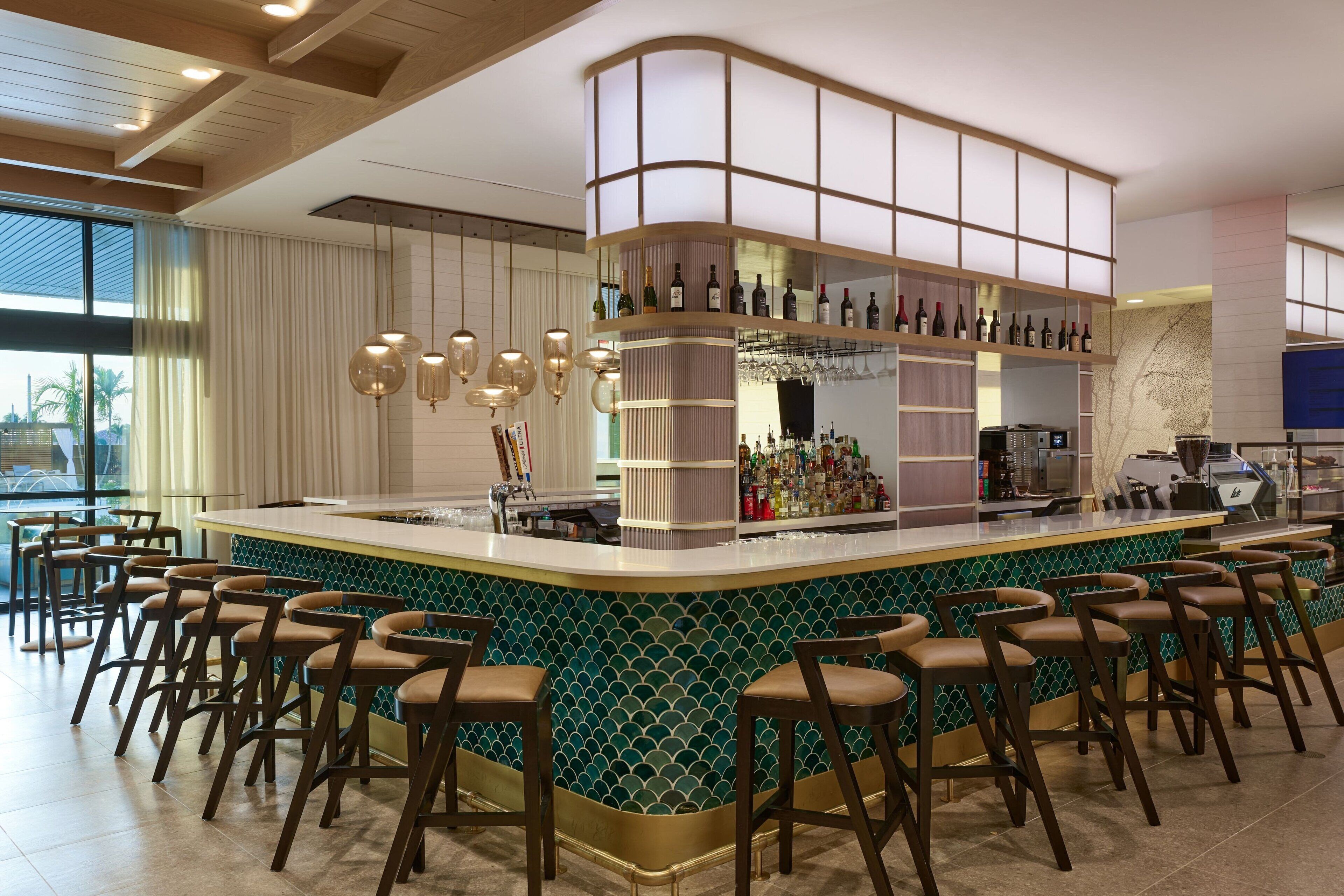 A bar area with a curved counter, multiple stools, and a variety of bottles and glasses.