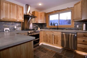 A modern kitchen with wooden cabinets, a stainless steel range, and a dishwasher.