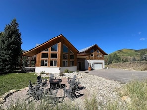 A two-story wooden house with a covered patio, a garage, and a gravel driveway.