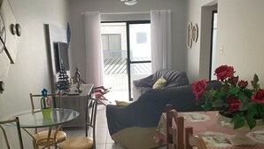 Una sala de estar con sofá, una mesa de comedor con sillas, un ventilador de techo y un balcón con barandilla.