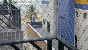 Una cerca de malla con vista a un edificio de varios pisos y balcones.