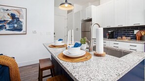Une cuisine moderne avec des armoires blanches, un comptoir en granit et un réfrigérateur en acier inoxydable.