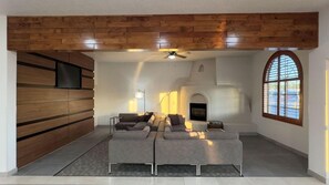 A modern living room with a sectional sofa, a fireplace, and a wooden accent wall. - Wingate by Wyndham Farmington NM (Farmington)