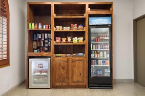 A compact kitchenette with a mini-fridge, a small refrigerator, and a shelf unit with various food items and beverages. - Wingate by Wyndham Farmington NM (Farmington)