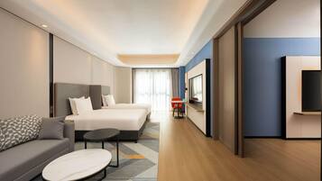 Una habitación de hotel moderna con una cama grande, un sofá, una mesita y un televisor.