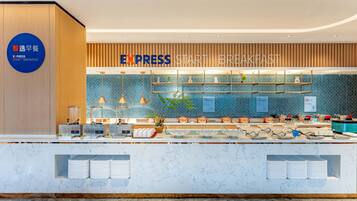 Un moderno espacio para desayuno tipo bufé, con un cartel que dice "EXPRESS START BREAKFAST" y un letrero azul que indica "Smart Breakfast Selection".