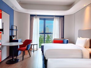 A modern hotel room with a bed, a desk, and a chair. There is a large window with curtains, and a cityscape is visible outside. - Holiday Inn Express Beijing Conference Center (Beijing)