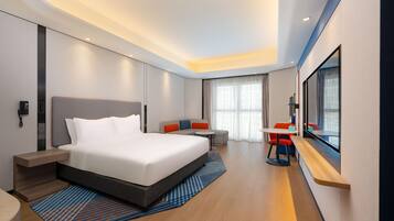 Una habitación de hotel moderna con una cama grande, un escritorio y una zona de estar.