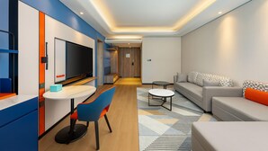 Habitació d'hotel moderna amb zona de menjador, un sofà i una televisió.