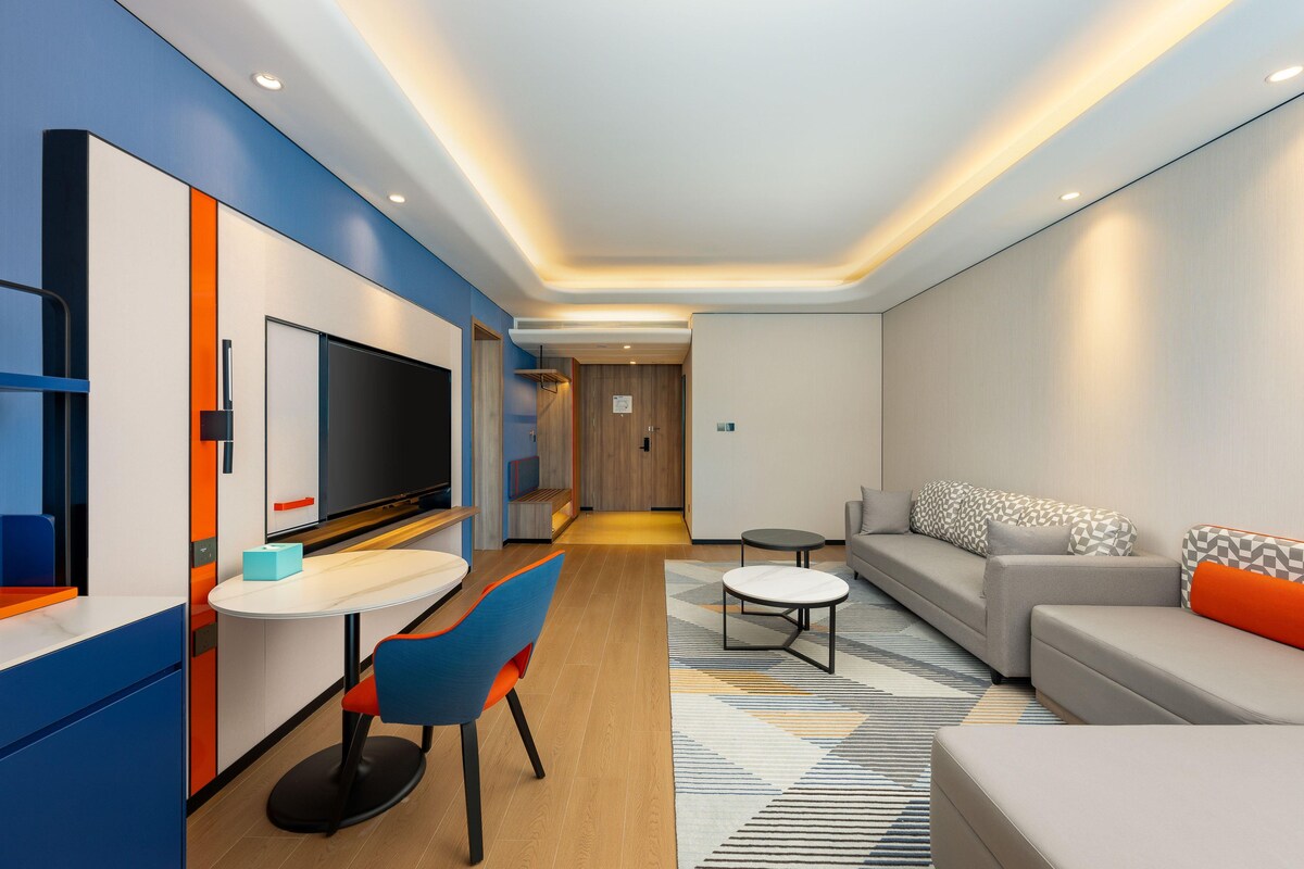 Et moderne hotelværelse med spiseplads, sofa og fjernsyn.