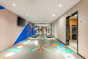 A hallway with treadmills, a TV mounted on the wall, and a laundry area. - Holiday Inn Express Beijing Conference Center (Beijing)